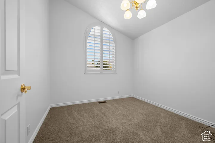Bedroom with an arched window with plantation shutters, neutral carpeting, and a multi-light ceiling fan
