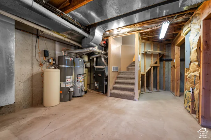 Unfinished basement featuring tandem water heaters, and furnace