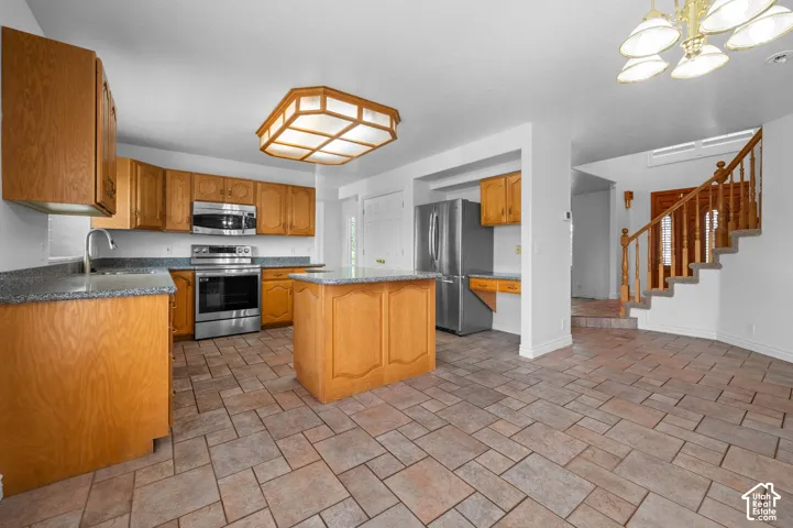 Kitchen featuring wood cabinetry, granite countertops, central island, stainless steel appliances, and tile flooring