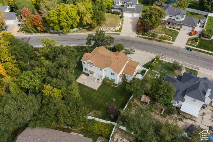 Aerial view of the back featuring a concrete patio, and mature tree canopy