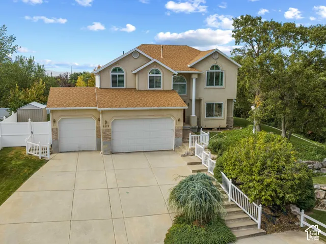 View of front of house featuring a stucco and brick exterior, an attached three-car garage, and arched windows