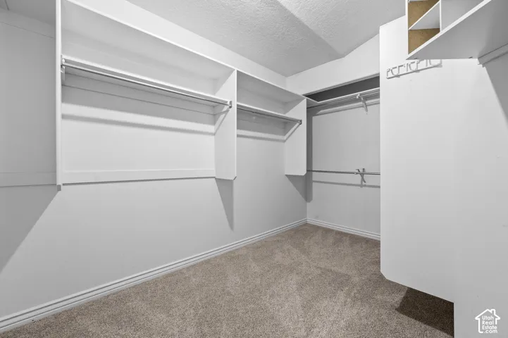 Primary bedroom walk-in closet featuring tiered shelving, built-in hanging rods, and overhead storage compartments