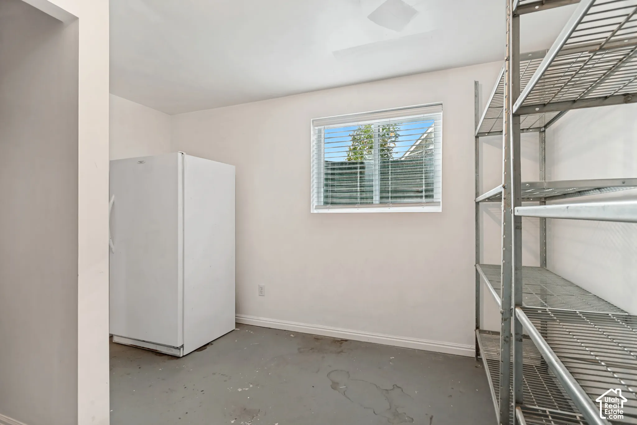 Utility room featuring neutral wall paint, a single window with horizontal blinds, and a hard-surface floor