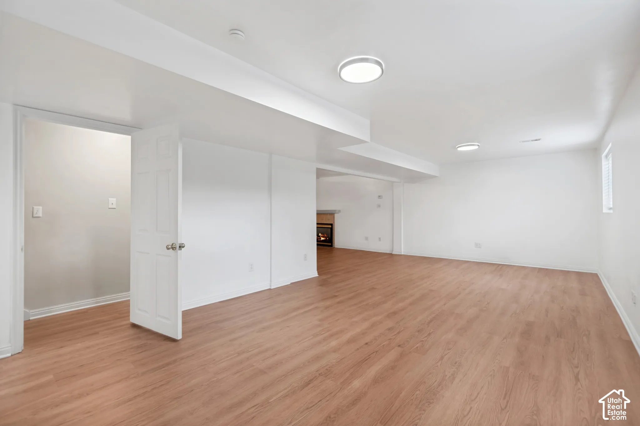 Open floor plan featuring wood-finish flooring, recessed lighting, and a fireplace with a mantel