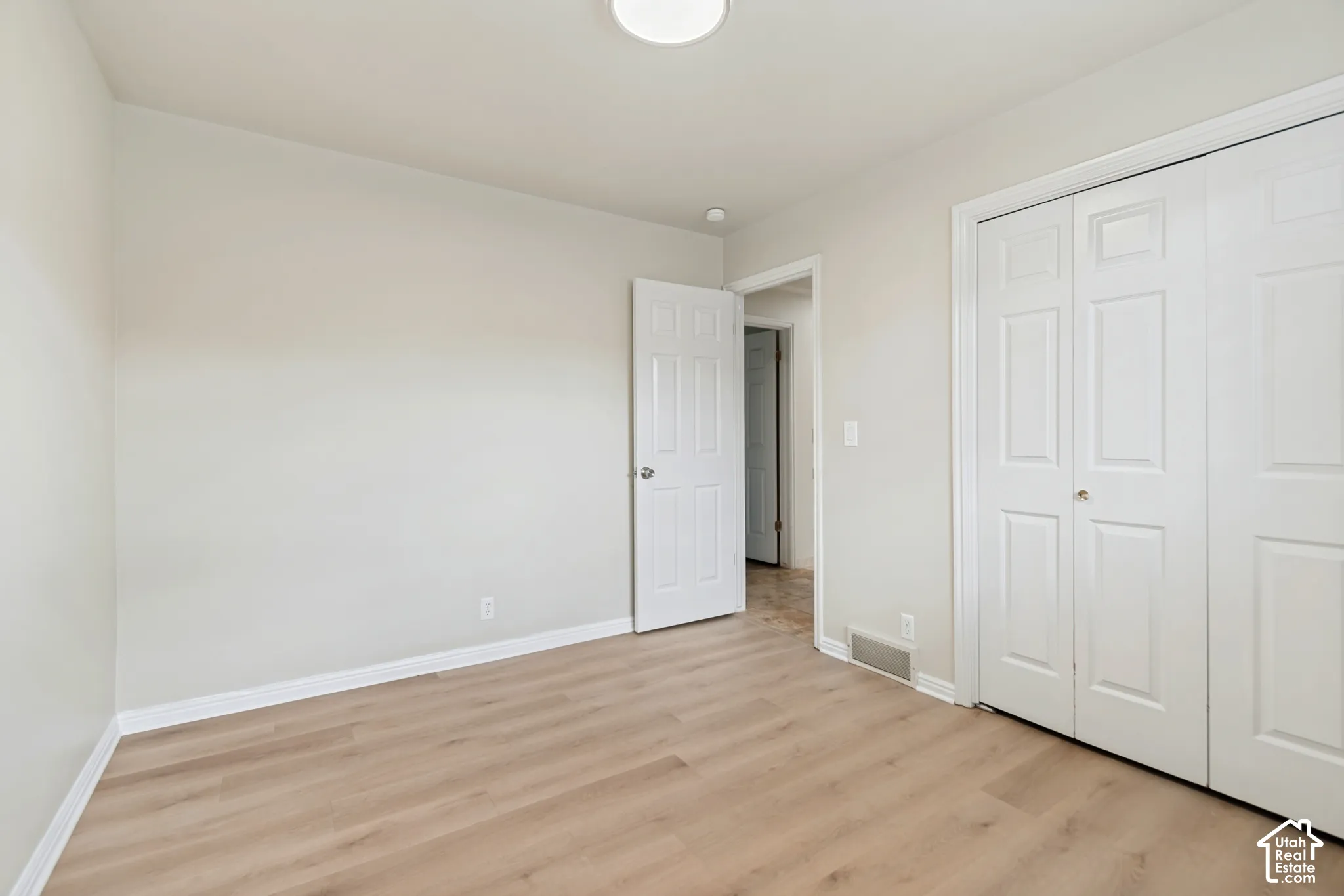 Neutral interior featuring wood-finish flooring, white paneled doors, and a double-door closet