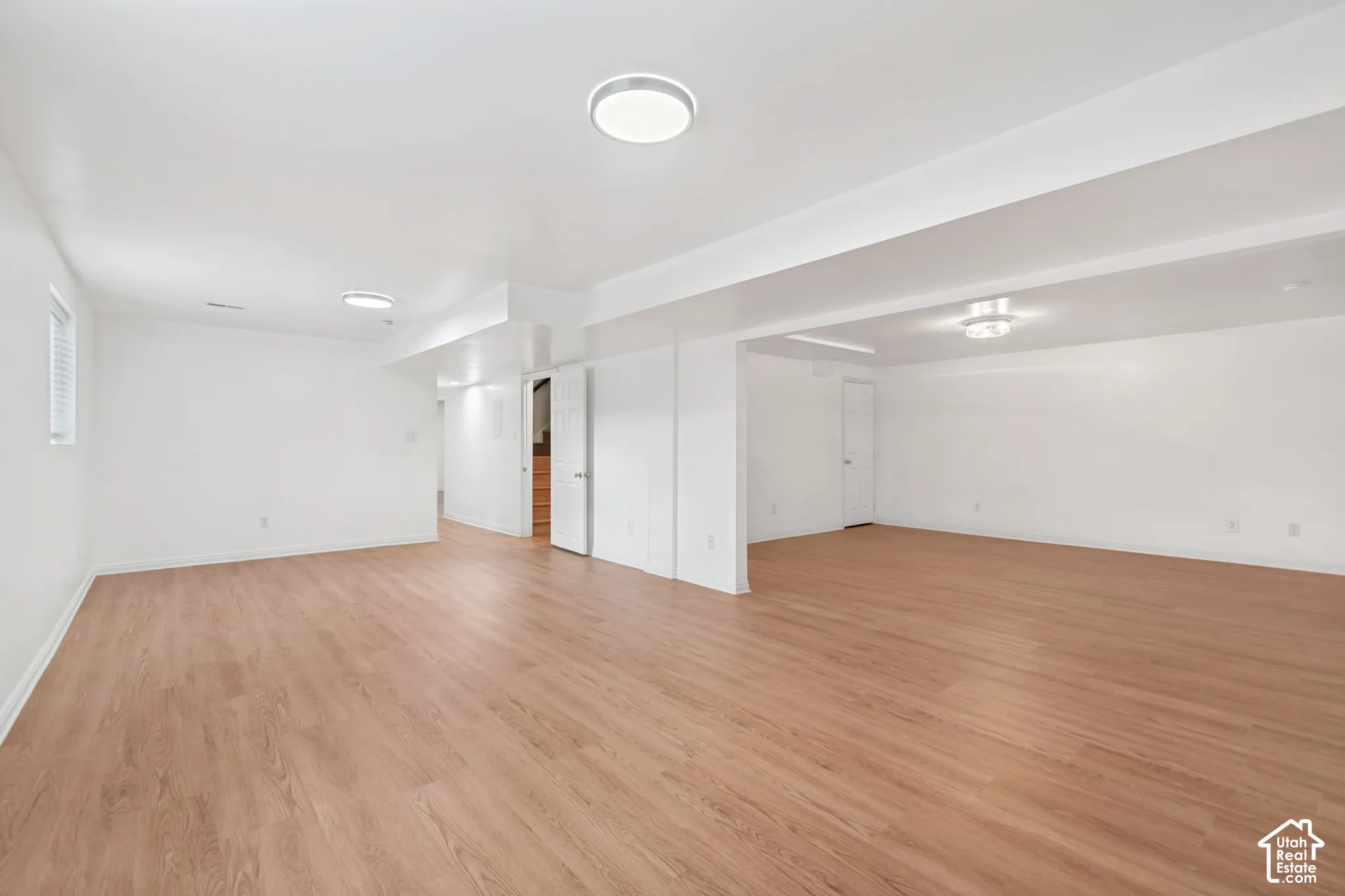 Open-concept space featuring wood-finish flooring, crisp white walls, and flush-mount ceiling lighting