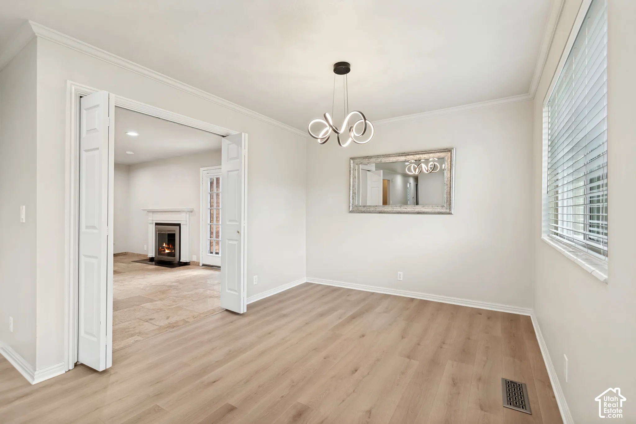 Room featuring wood-finish flooring, a modern multi-ring chandelier, and double-hinged folding doors