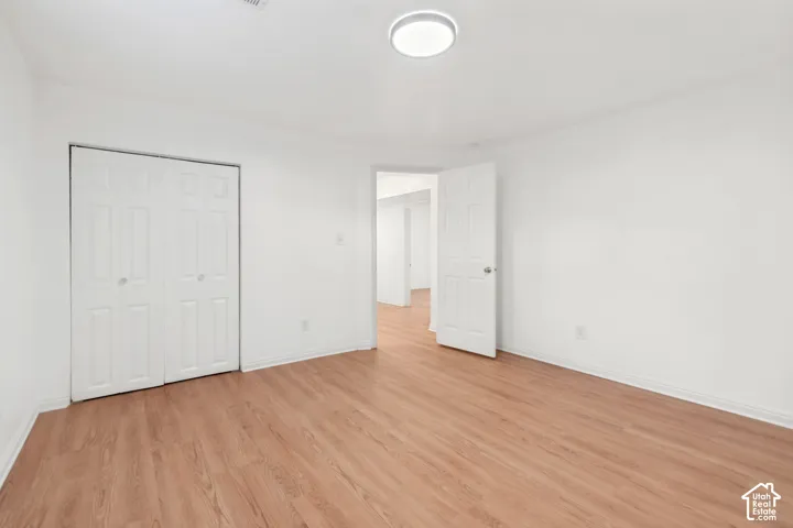 Neutral interior space featuring wood-finish flooring, white walls, flush-mount ceiling lighting, and a bi-fold closet door