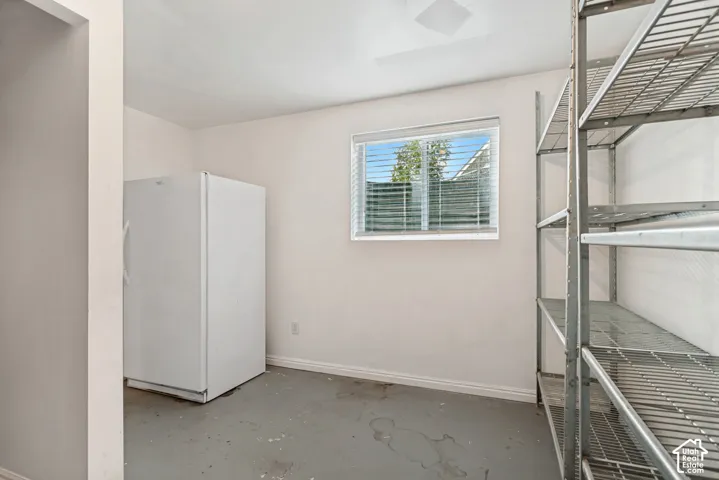 Utility room featuring neutral wall paint, a single window with horizontal blinds, and a hard-surface floor