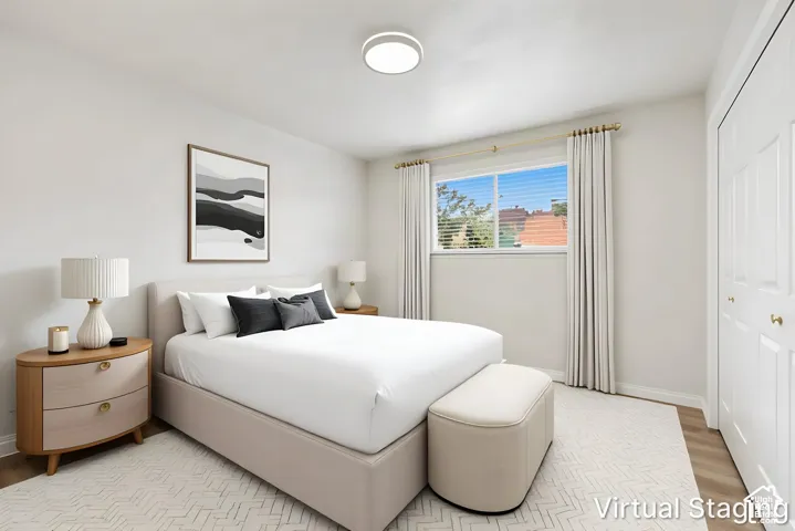 Neutral-toned interior room featuring wood-finish flooring, a large sliding window, a circular flush-mount ceiling light fixture, and double-door reach-in closet cabinetry
