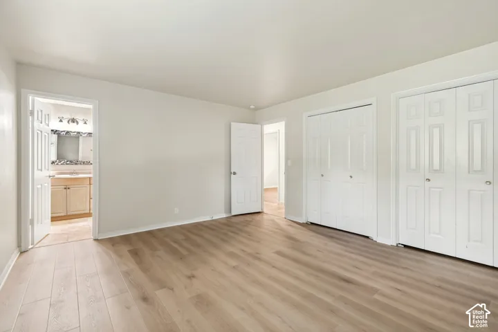 Neutral-toned interior featuring wood-finish flooring, dual bi-fold door closets, and solid-core interior doors
