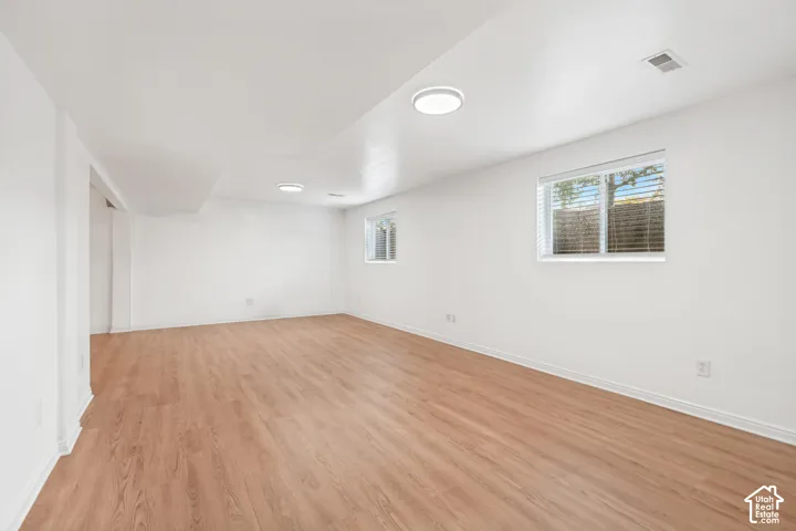 Neutral interior space featuring wood-finish flooring, crisp white walls, and dual flush-mount ceiling light fixtures