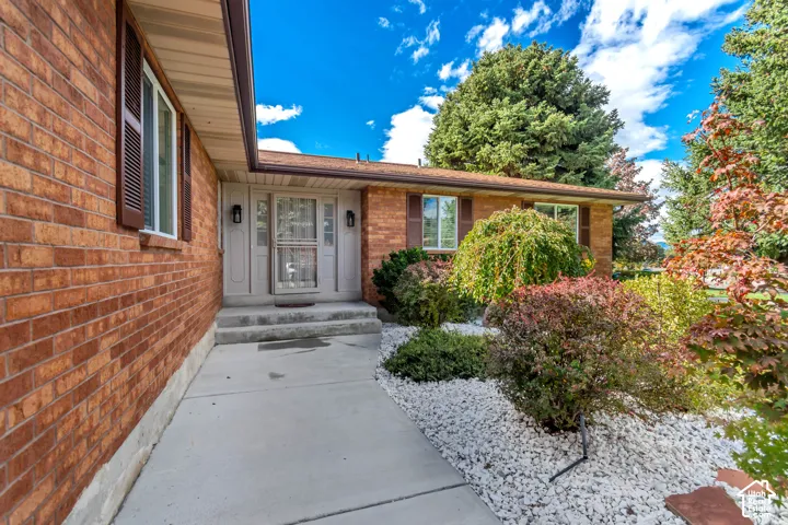 Brick exterior facade featuring louvered shutters, concrete walkway, and rock garden landscaping