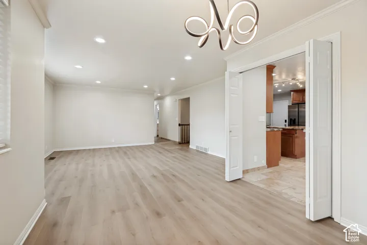 Open-concept interior featuring wood-finish flooring, recessed lighting, a modern sculptural chandelier, and white bi-fold doors