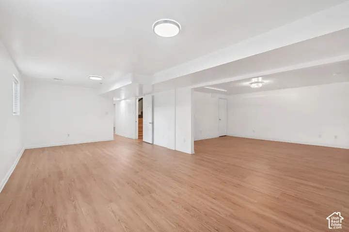 Open-concept space featuring wood-finish flooring, crisp white walls, and flush-mount ceiling lighting