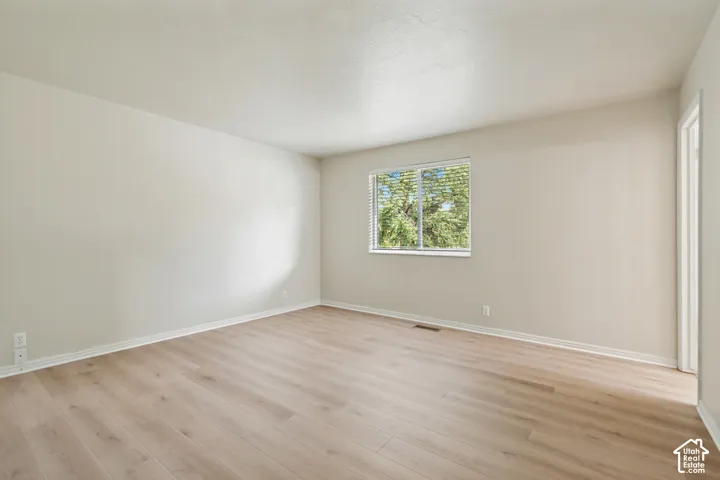 Neutral-toned interior space featuring wood-finish flooring, smooth wall surfaces, and a sliding window