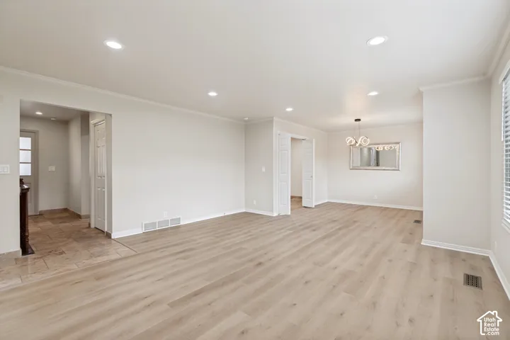 Open-concept living space featuring wood-finish flooring, recessed lighting, multi-panel interior doors, and a decorative chandelier