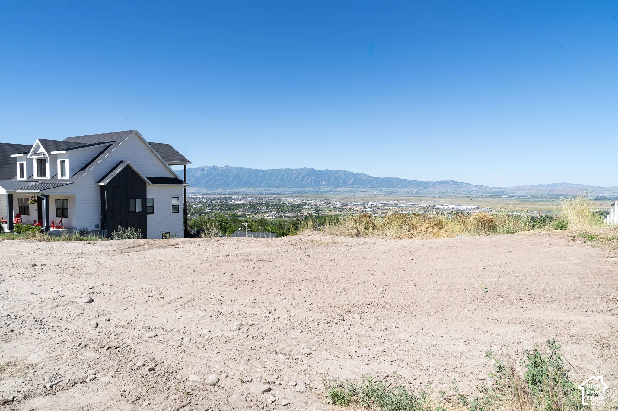 Expansive lot featuring mountain and valley scenery, highlighted by a contemporary two-story structure with multi-gabled rooflines and a dual-tone exterior finish