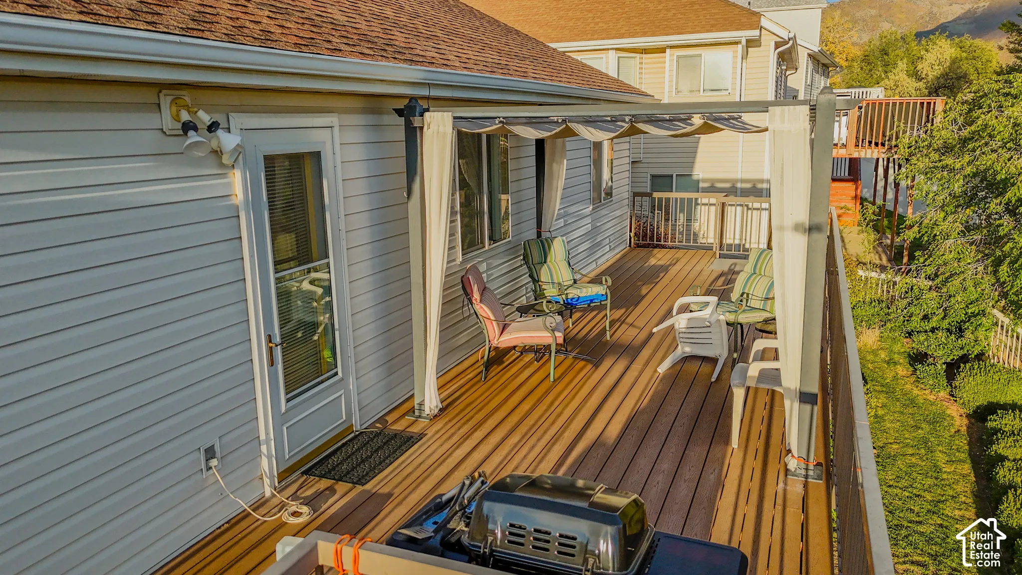 Elevated composite deck featuring a metal-frame pergola with retractable fabric canopy, horizontal vinyl siding, and metal railing