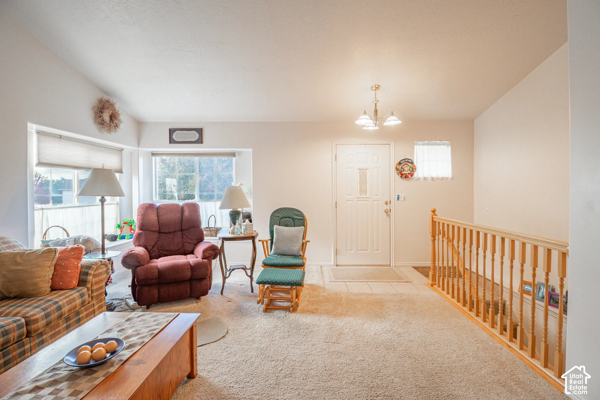 Open-concept space featuring a vaulted ceiling, large picture window with a built-in window seat, natural wood railing, and an entry door with a decorative glass panel