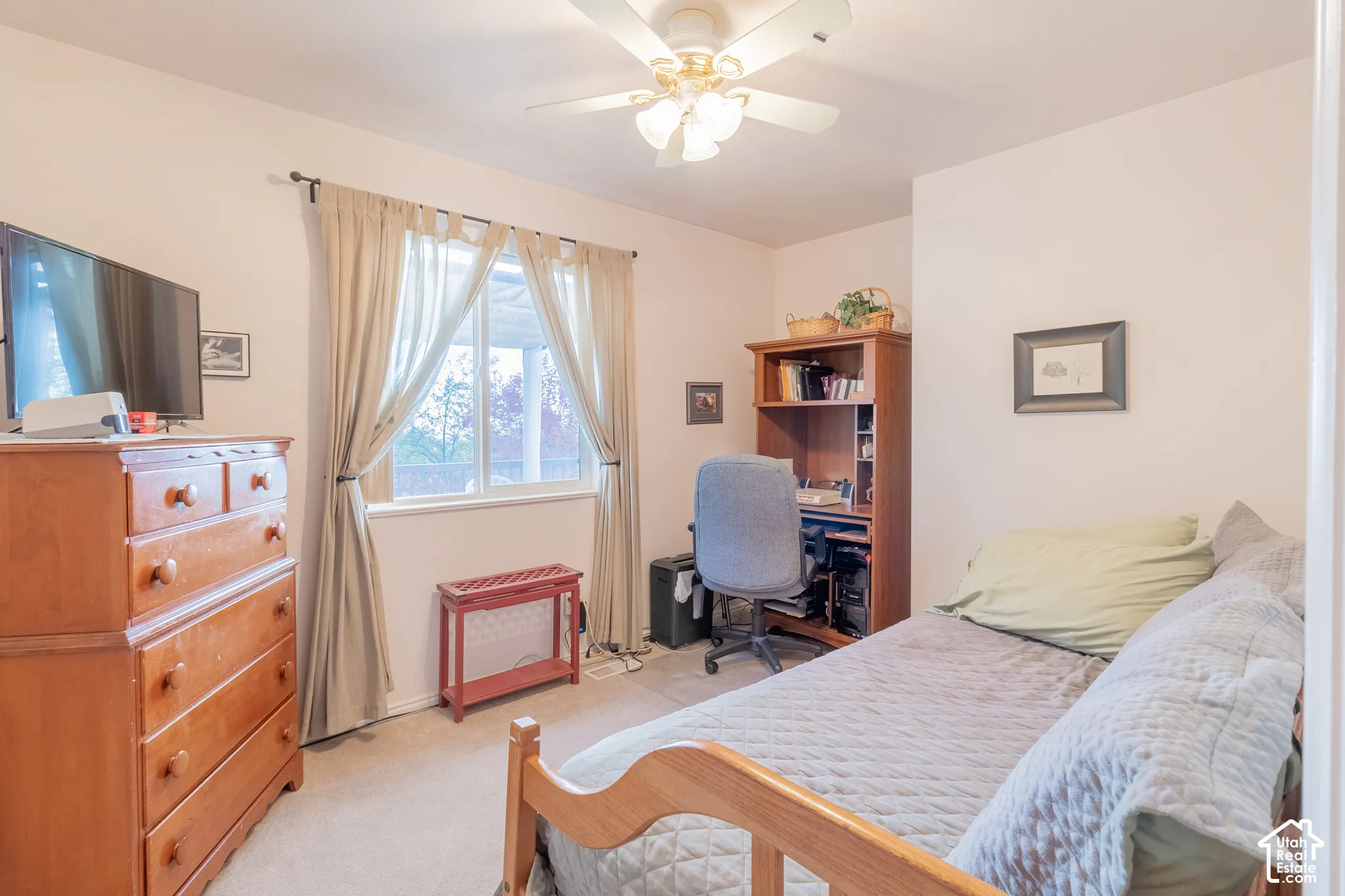 Neutral wall tones, carpeting, ceiling-mounted fan with integrated lighting, and a window with exterior exposure
