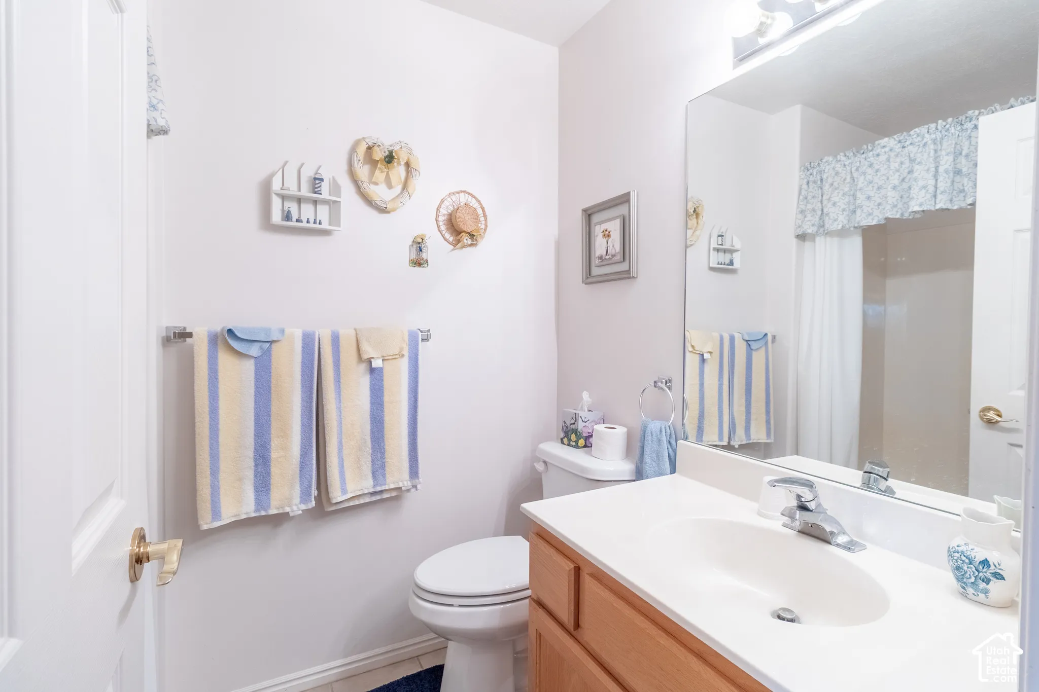 Bathroom featuring a wood-finish vanity with a molded countertop and integrated sink, a full-width vanity mirror, a multi-light fixture, and a tub-shower combination