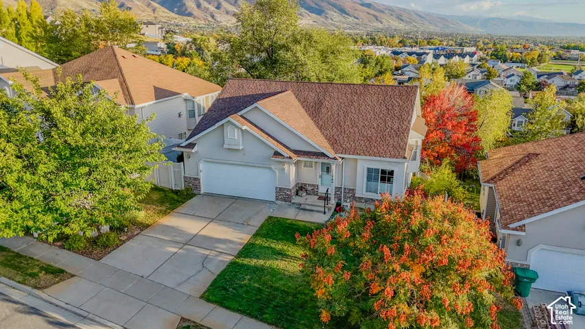 Single-family residence featuring a stucco and stone exterior, asphalt shingle roof, two-car garage, concrete driveway, and mature landscaping