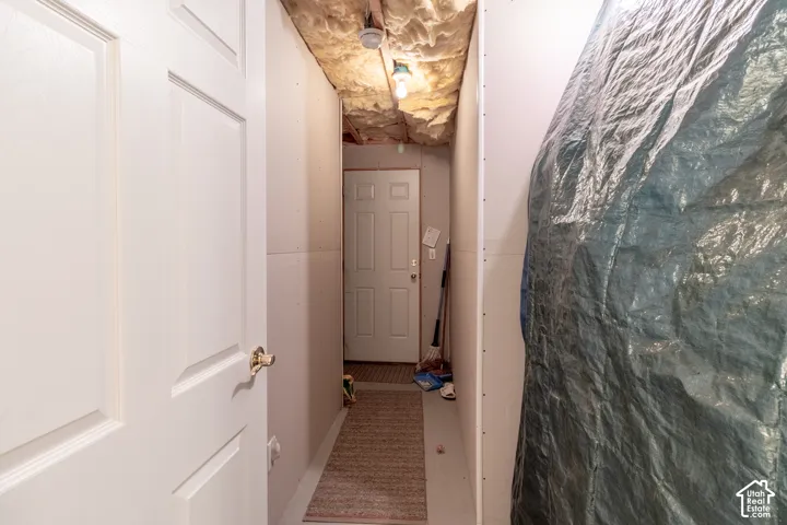 Utility area featuring unfinished insulation, drywall panels, and an exterior-grade door
