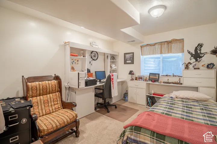 Built-in white cabinetry and integrated desk workstation, wall-to-wall carpeting, and a window with horizontal blinds