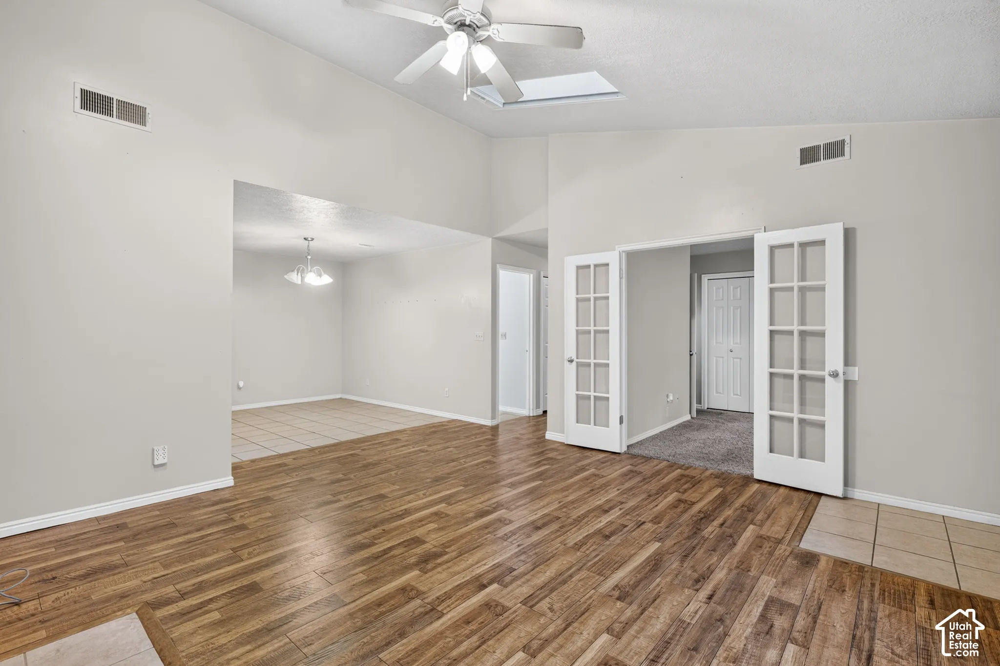 Vaulted ceilings featuring a skylight, wood-finish flooring, and French doors