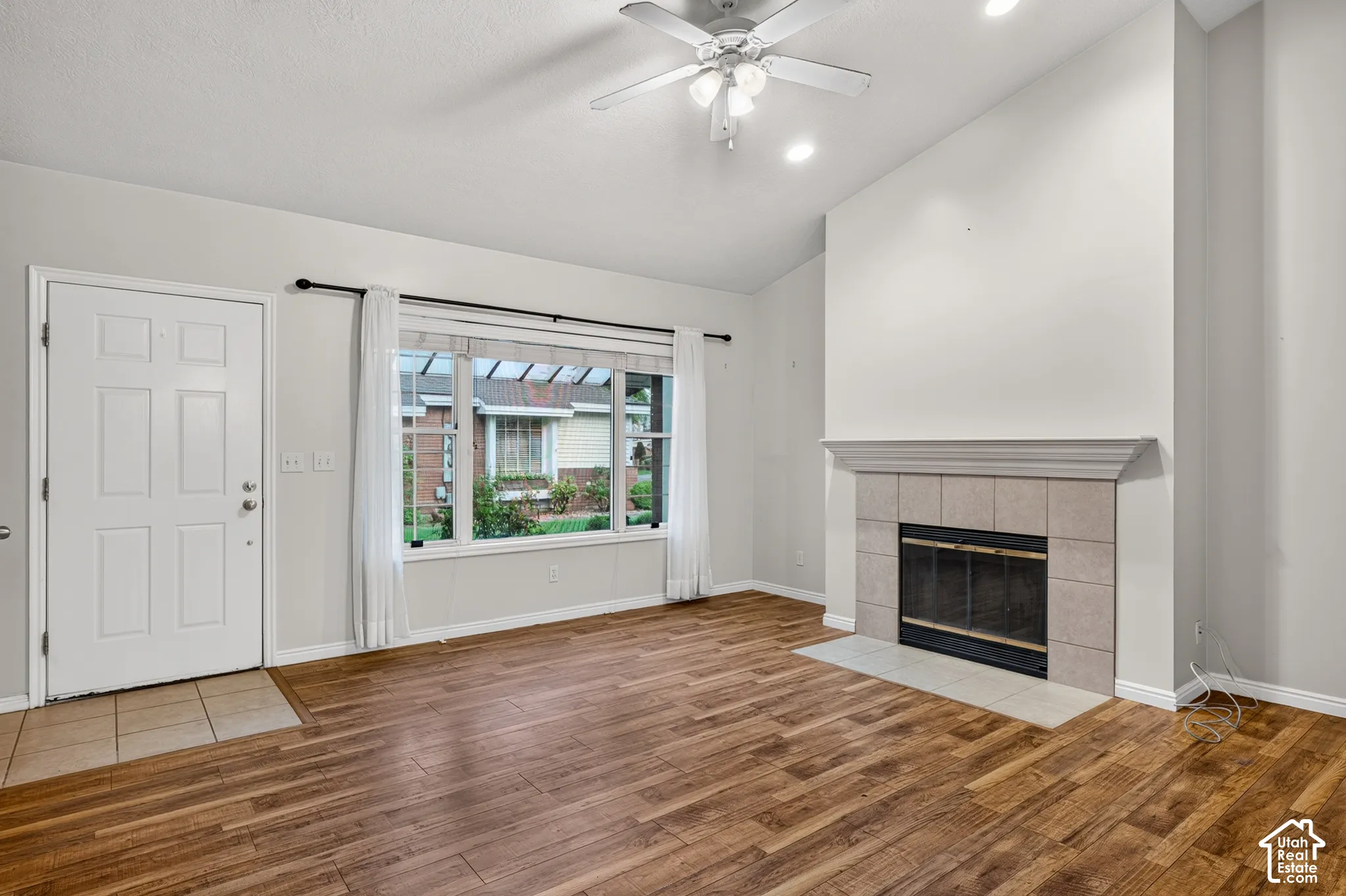 Vaulted ceilings, wood-finish flooring, and a fireplace featuring a tile surround and mantel