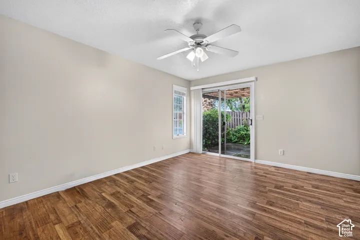 Room featuring wood-finish flooring, a ceiling fan with integrated lighting, a single window, and a sliding glass door