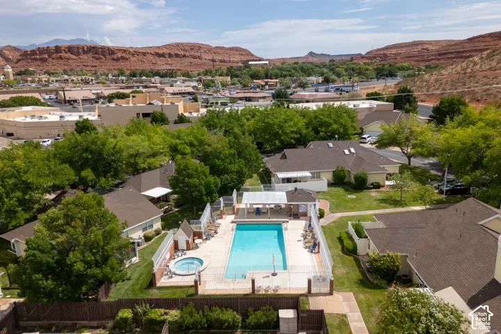 Community swimming pool and hot tub featuring a concrete patio, perimeter fencing, and a covered pavilion