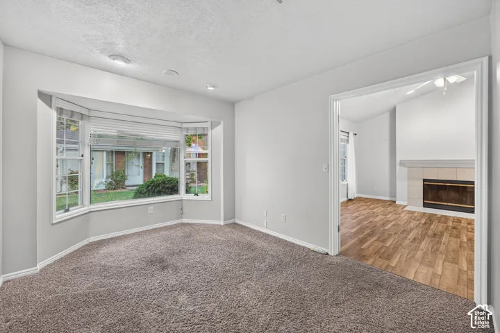 Bay window with multi-pane glass, recessed ceiling lighting, and wide entryway revealing wood-finish flooring and a tiled fireplace surround