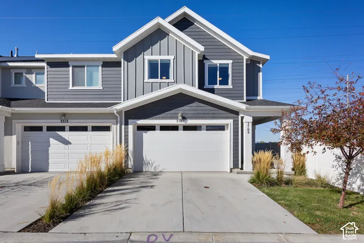 Exterior facade featuring horizontal and vertical siding, dual-pitched rooflines, two-car garage with overhead door, and concrete driveway