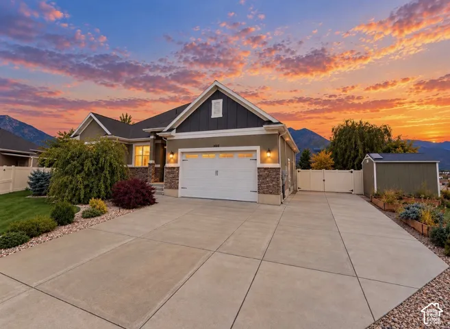 Exterior featuring a two-car garage, stone veneer accents, board-and-batten siding, concrete driveway, and mountain backdrop
