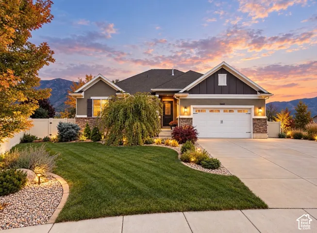 Single-story residence featuring a stone and siding exterior, two-car garage, manicured lawn, and low-maintenance landscaping with decorative rock beds