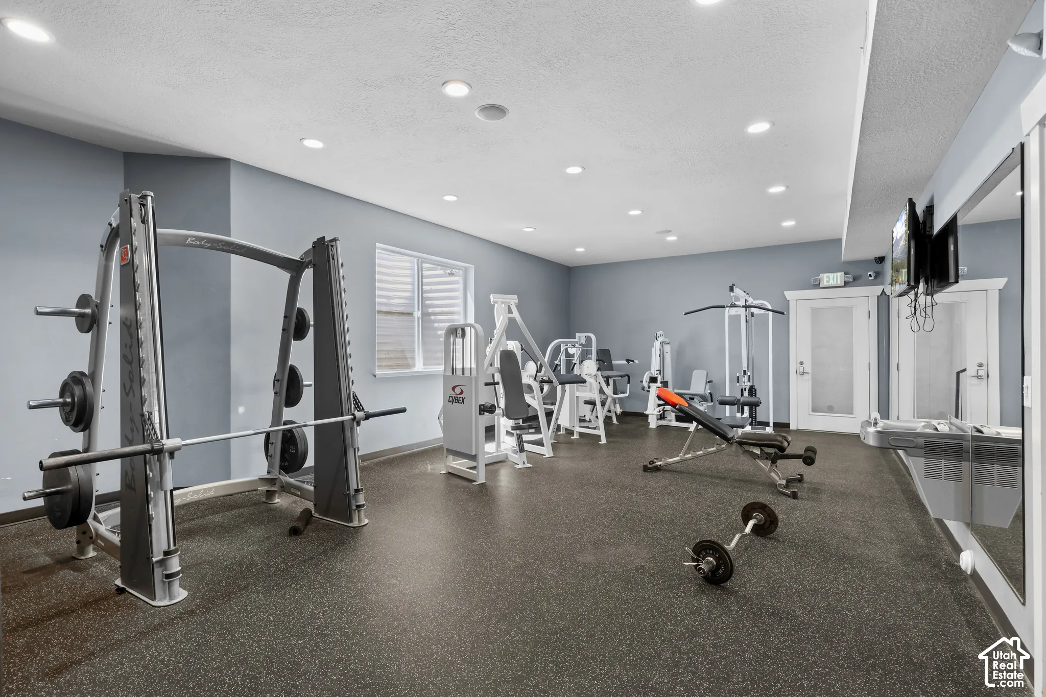 Interior space featuring recessed lighting, durable rubberized flooring, light-toned wall finishes, and a wall-length mirror