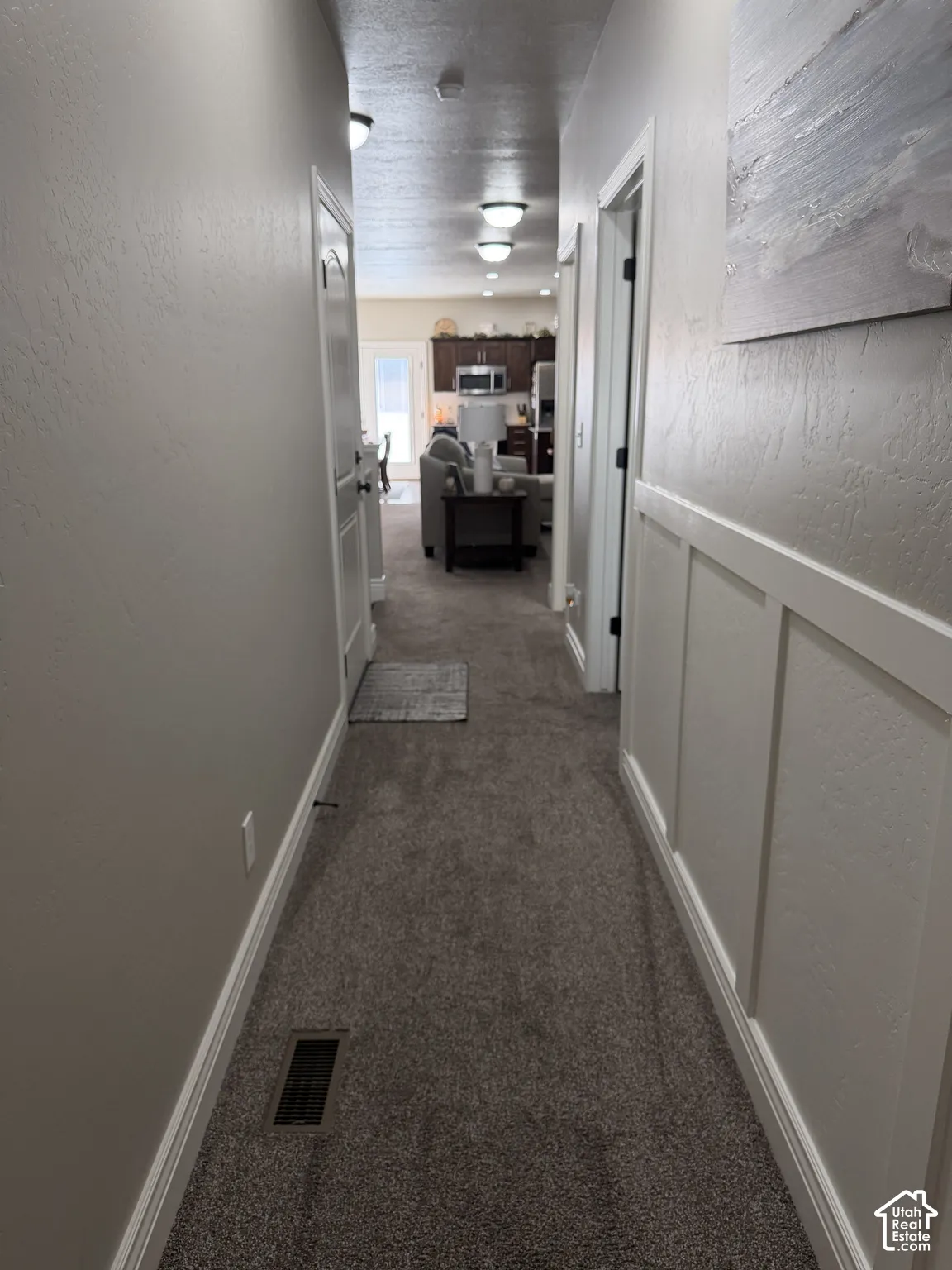 Hallway featuring textured walls, white board-and-batten wainscoting, carpeted flooring, and recessed ceiling lighting