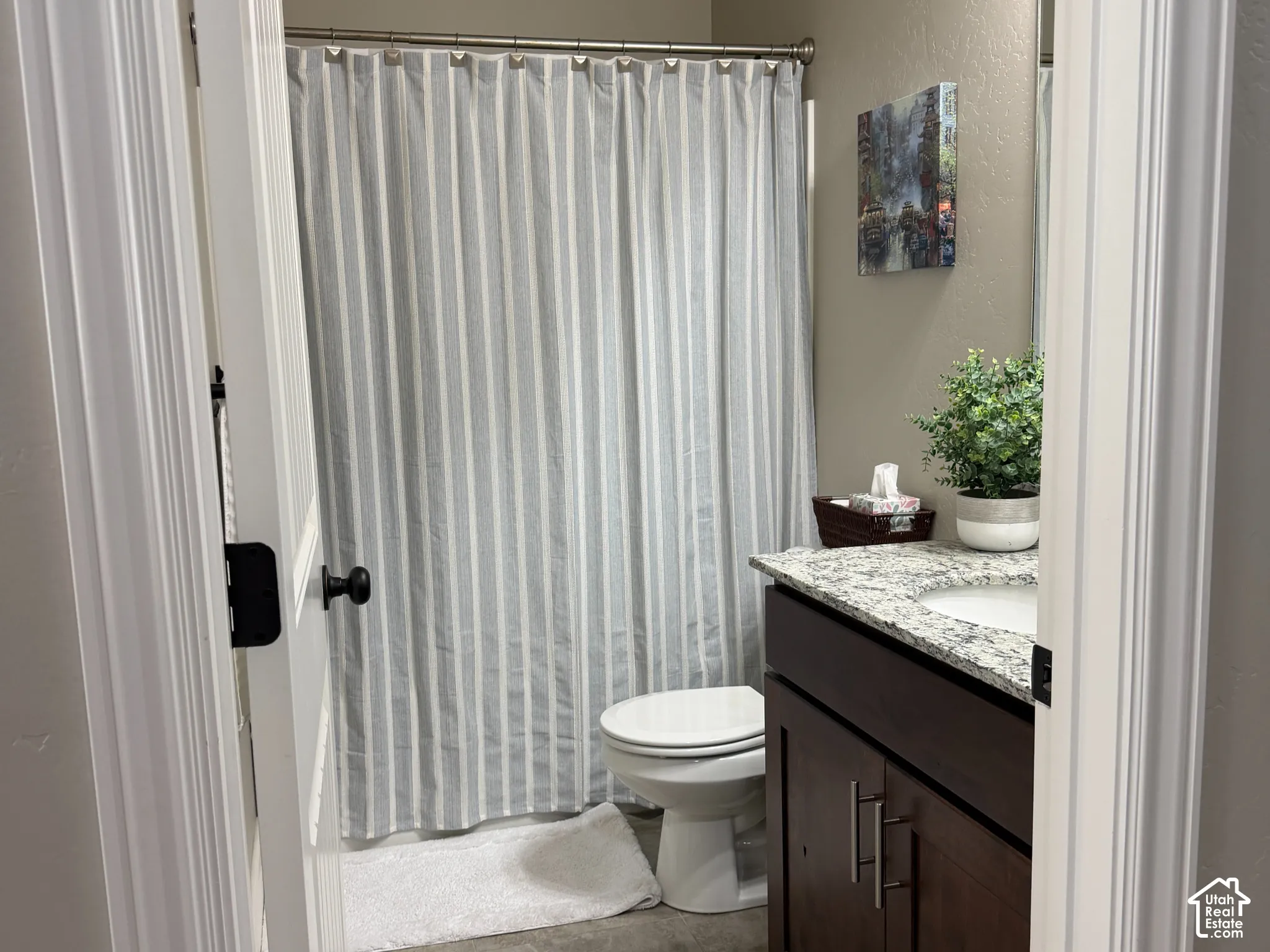 Dark wood vanity with a stone-finish countertop, undermount sink, and tile flooring