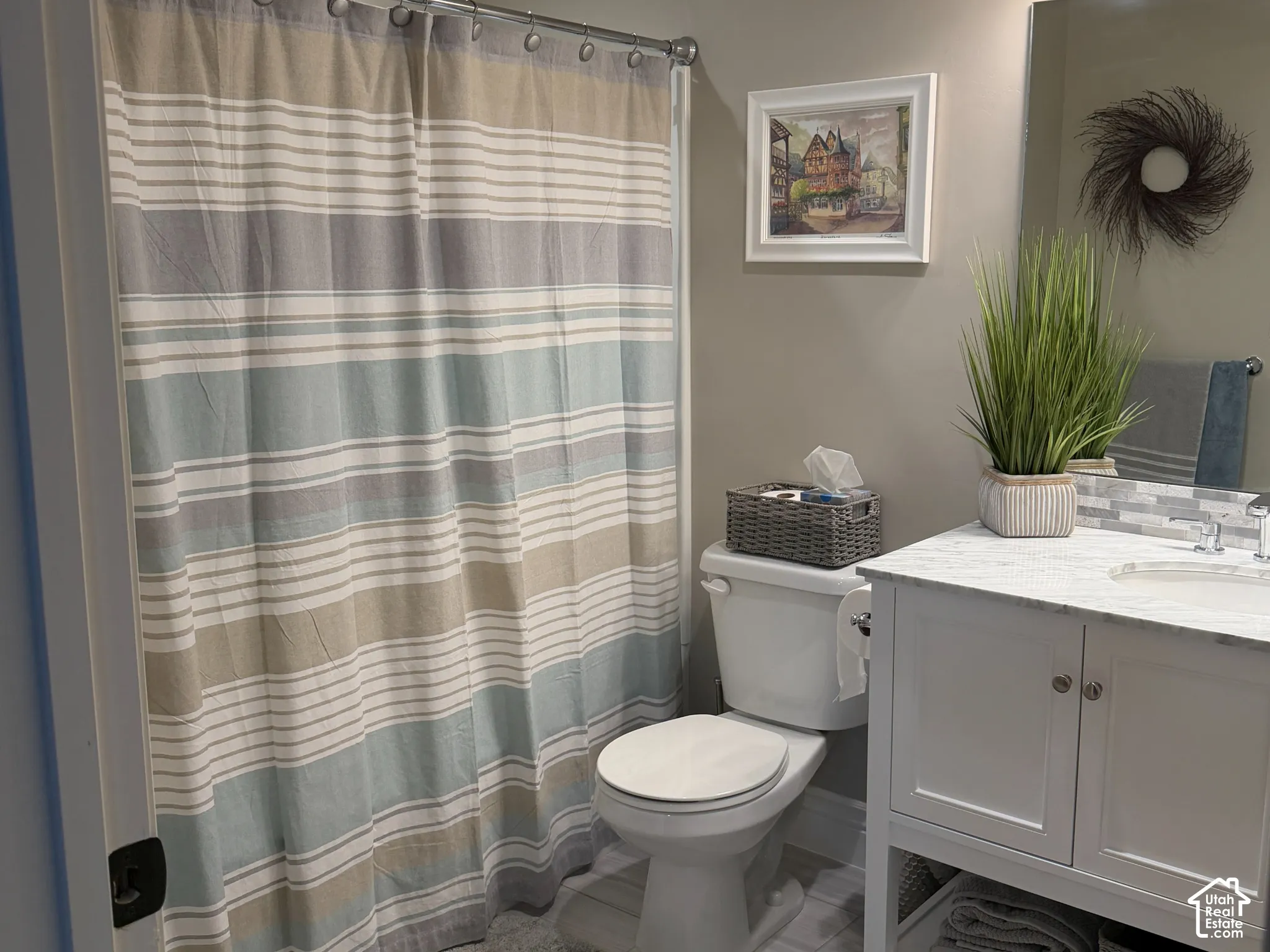 White vanity with stone countertop, undermount sink, tiled backsplash, and tub-shower combo.
