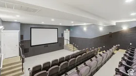 Dedicated media room featuring a large projection screen, tiered seating platforms, wall-mounted acoustic panels, and recessed ceiling lighting