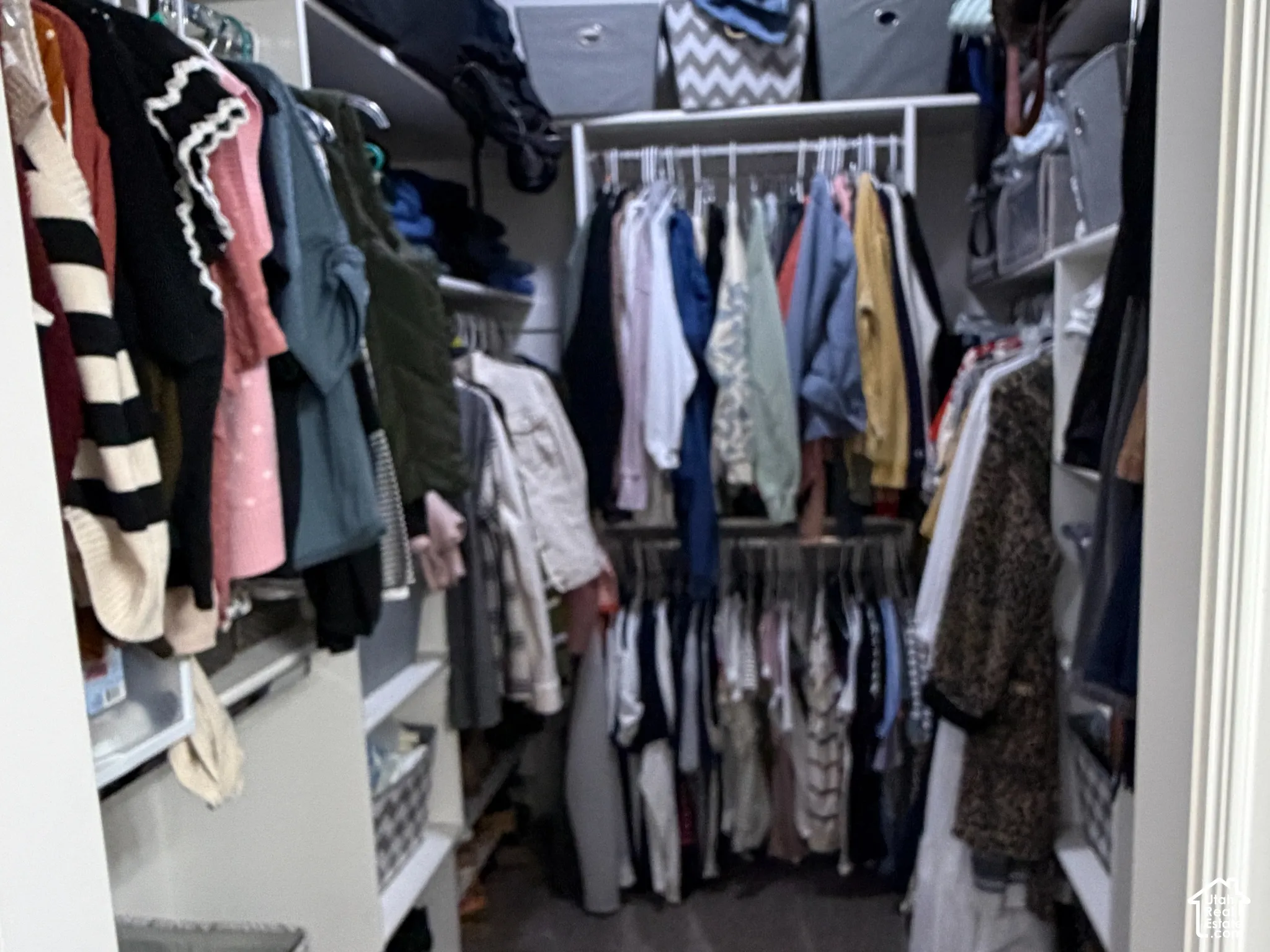Walk-in storage space featuring tiered built-in shelving and dual-level hanging rods