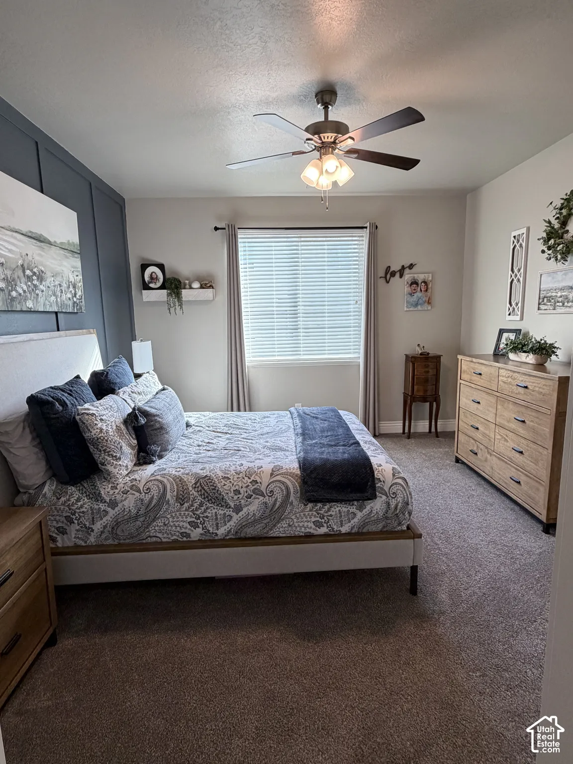 Bedroom featuring a charcoal-painted accent wall with vertical board-and-batten detailing, neutral wall-to-wall carpeting, and a central ceiling fan with integrated lighting