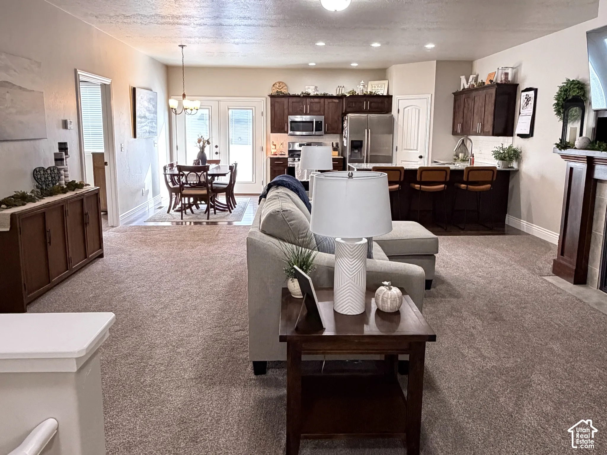 Open-concept interior featuring dark wood cabinetry, a built-in kitchen island, a fireplace with a wood mantel, and full-glass panel doors