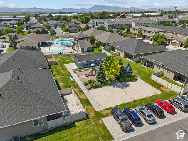 Aerial perspective featuring community amenities including a swimming pool with water feature, playground area, sand volleyball court, and covered pavilion