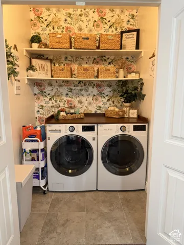 Utility area featuring floral wallpaper, dual white built-in storage shelves, dark wood-finish countertop, and stone-finish tile flooring