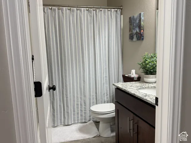 Dark wood vanity with a stone-finish countertop, undermount sink, and tile flooring