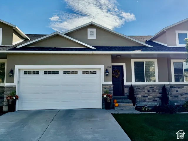 Exterior facade featuring a multi-gabled roofline, stone and stucco exterior, with an attached two-car garage, and a concrete driveway