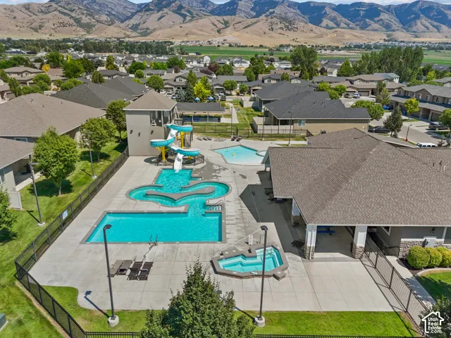 Community recreation facility featuring an outdoor swimming pool, integrated waterslide, spa, and covered pavilion, set against a backdrop of prominent mountain terrain